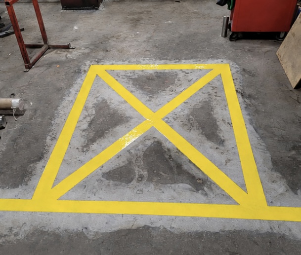Concrete floor with bright yellow safety line X marking